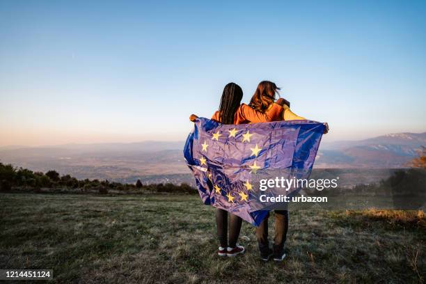 two multi-ethnic women holding european union flag - continental stock pictures, royalty-free photos & images