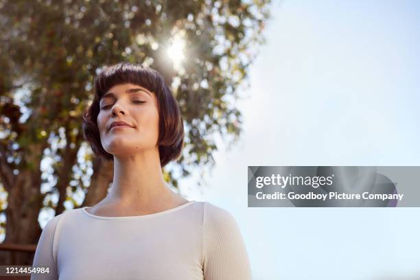 junge frau steht draußen und meditiert mit geschlossenen augen - man closed eyes stock-fotos und bilder