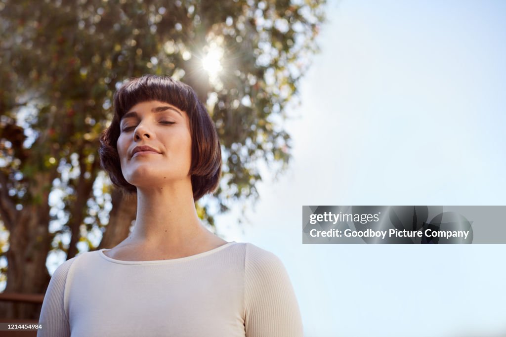Jonge vrouw die zich buiten bevindt en met gesloten ogen mediteert