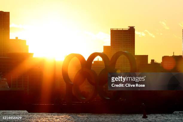 The sun sets behind the Olympic rings in Odaiba marine park on March 24, 2020 in Tokyo, Japan. Although an official decision is yet to be announced,...