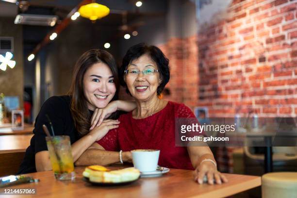 porträtt av vacker mor och dotter i en restaurang som omfamnar varandra - mother daughter brunch bildbanksfoton och bilder