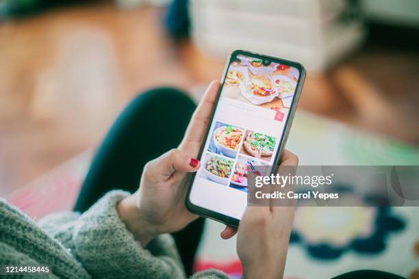 woman using meal delivery service through mobile app. - young man groceries kitchen stock-fotos und bilder