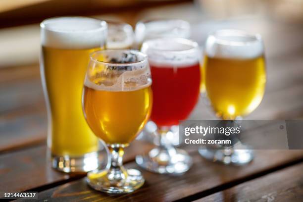 vielfalt an craft-bier auf einem holztisch - handwerklich gebrautes bier stock-fotos und bilder