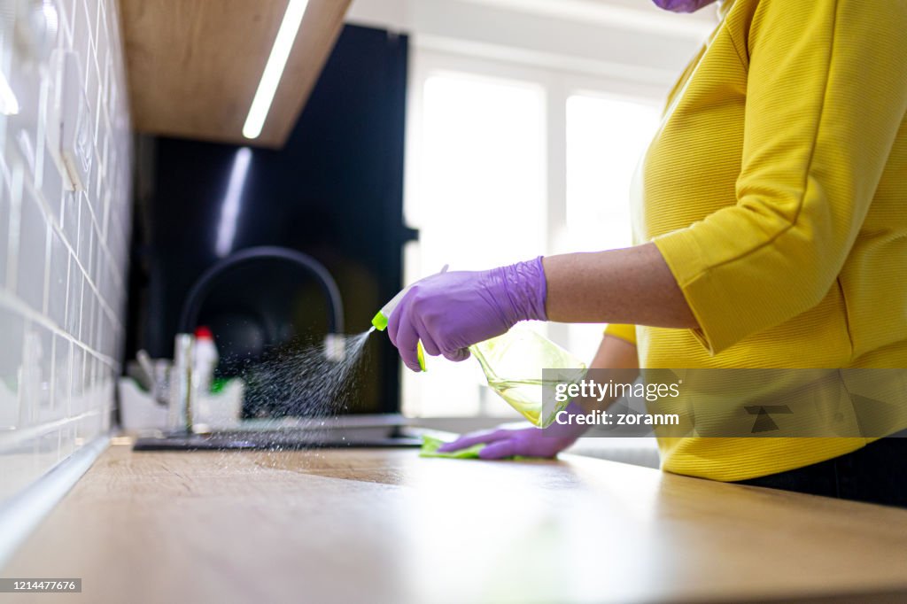 Desinfección del contador de la cocina en guantes de protección