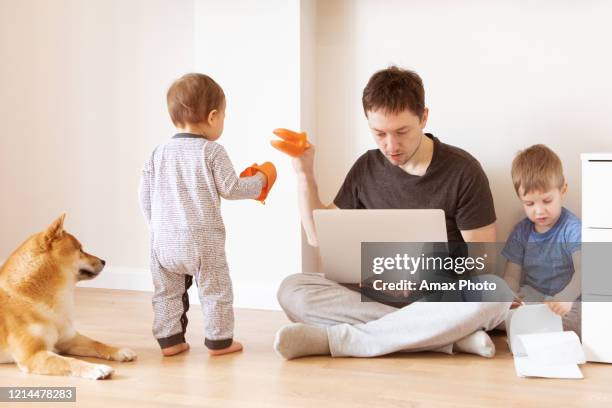 vater arbeitet im home office, während die kinder spielen. home office und telekommunikationskonzept - abstand halten infektionsvermeidung stock-fotos und bilder