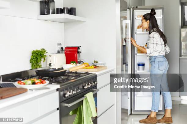 frau auf der suche nach lebensmitteln im kühlschrank in der küche - fridge door stock-fotos und bilder