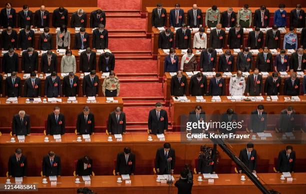 Chinese president Xi Jinping, center, and top members of government and delegates, many wearing masks, bow their heads as they observe one minute of...