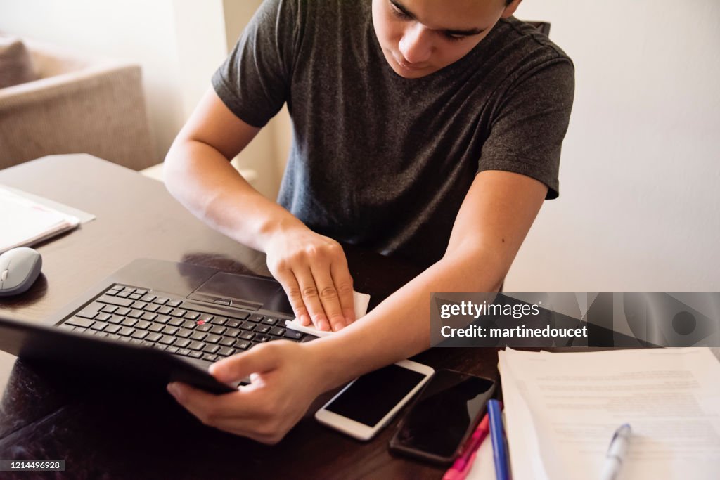 十幾歲的男孩在家學習時擦筆記本電腦。