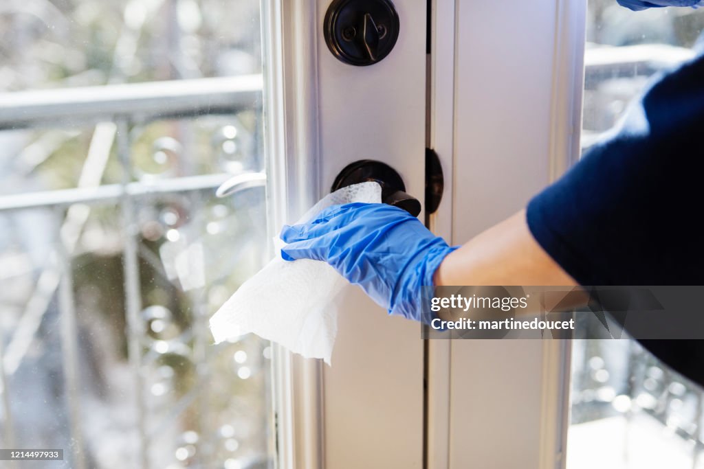 Hand with glove wiping door handle.