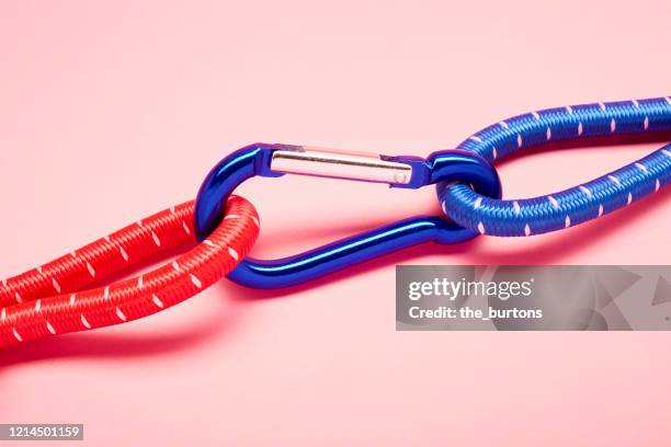 blue carabiner with red and blue ropes on pink background - sicherheitsmaßnahme stock-fotos und bilder