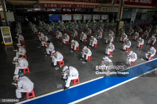 Employees eat their lunch while staying 2 meters away from each other at the Dongfeng Fengshen plant on March 24, 2020 in Wuhan, Hubei province,...