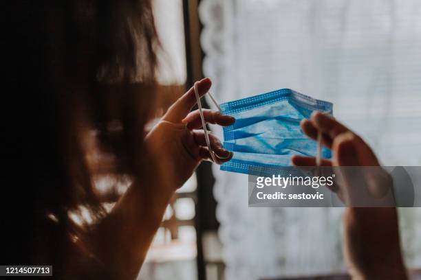 woman is holding a covid-19 anti-coronavirus mask as protection against infection - protective face mask stock pictures, royalty-free photos & images