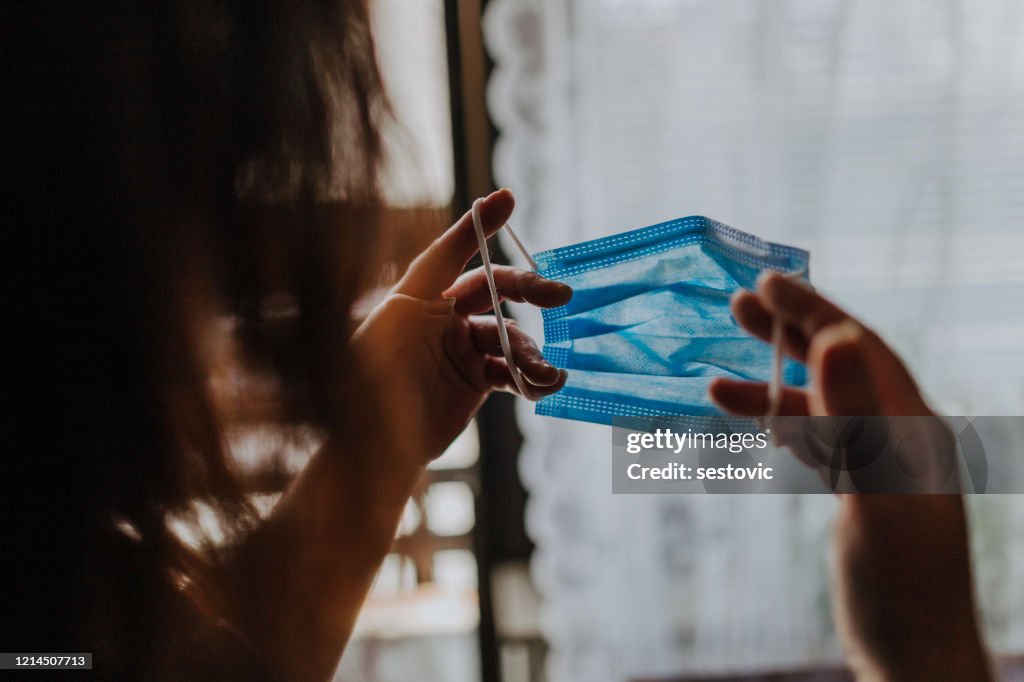 Woman is holding a COVID-19 anti-coronavirus mask as protection against infection