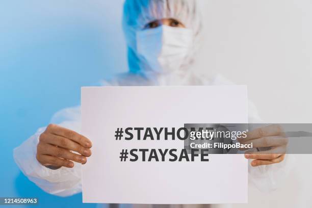 nurse/doctor holding a paper with a message for people to stay at home - state of emergency stock pictures, royalty-free photos & images