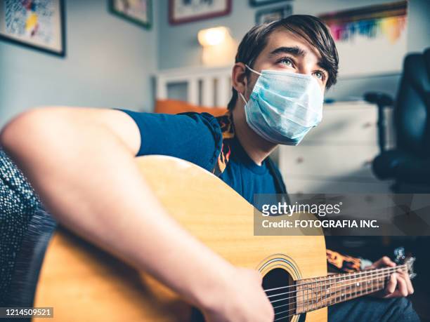 covid-19, teenager playing guitar in his room - masked musicians stock pictures, royalty-free photos & images