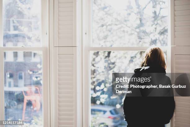 a woman looking through the window... social distancing. - embuscade photos et images de collection