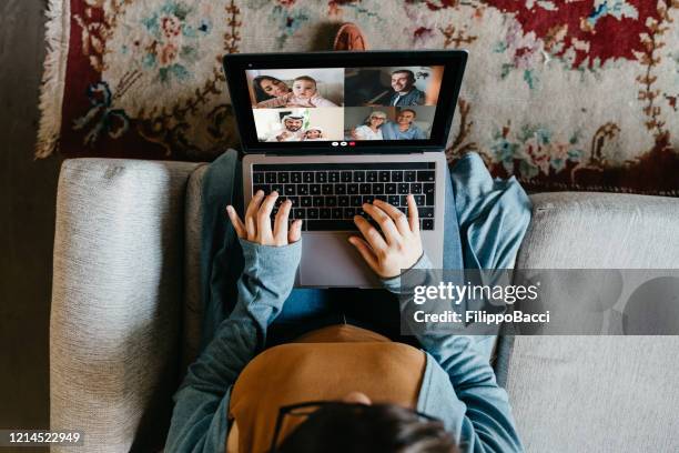 jovem usando um laptop para se conectar com seus amigos e pais durante a quarentena - distanciamento social - fotografias e filmes do acervo