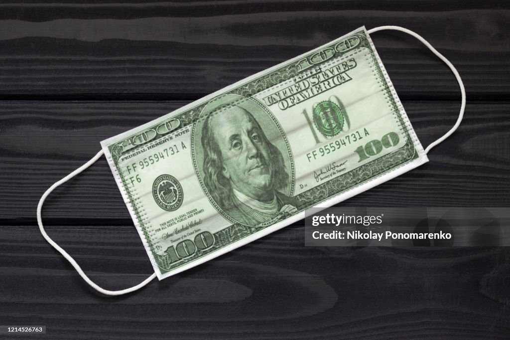 Dollar shaped medical mask on a dark background the concept of making money on infection protection