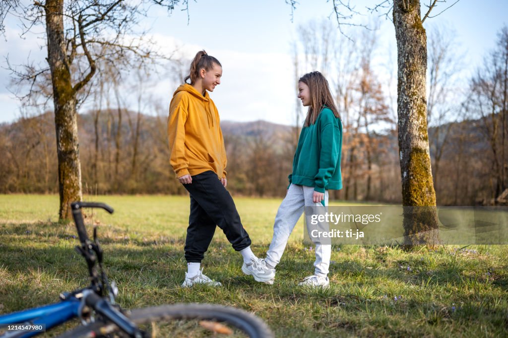 Two school girls using tapping as an alternative handshake outdoors in nature