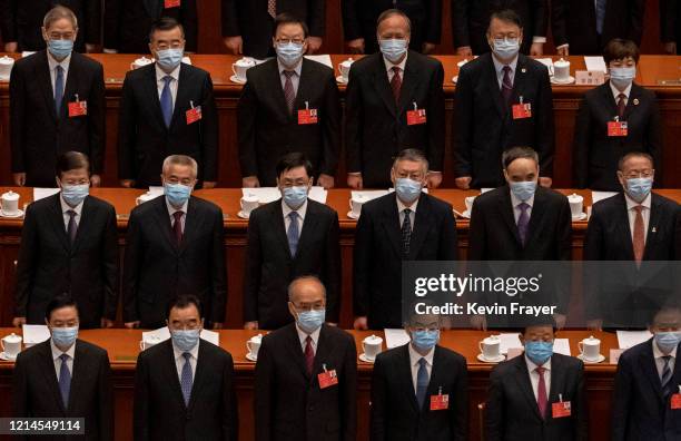 Chinese Communist Party delegates, all wearing protective masks, stand during the national anthem at the opening of the National People's Congress at...