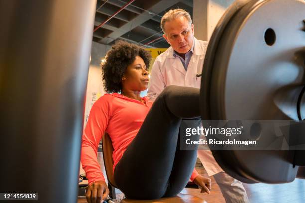 afro-kolumbianische frau mit ihrem arzt in einem fitnessstudio - sportmedizin happy stock-fotos und bilder