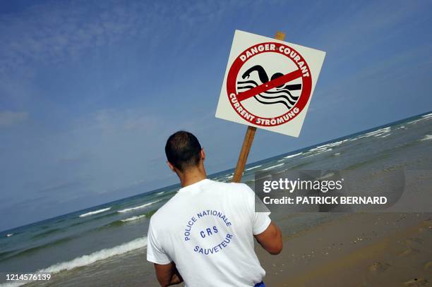 Un CRS maître-nageur installe un panneau indiquant les courants de baïne, le 21 juillet 2004 sur la plage de Lacanau. Ces courants dangereux, qui...