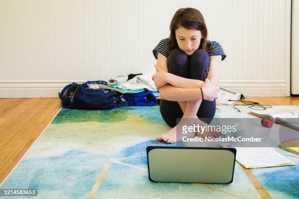 sad female teenager watching media on laptop hugging herself - topnews stock pictures, royalty-free photos & images