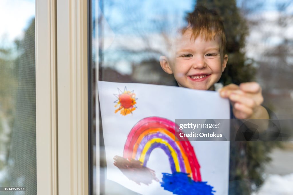 Young Boy attacca il suo disegno alla finestra di casa durante la crisi covid-19