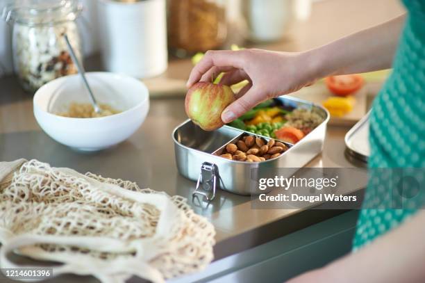 woman packing vegan food into plastic free lunchbox at home. - lunch box stock-fotos und bilder