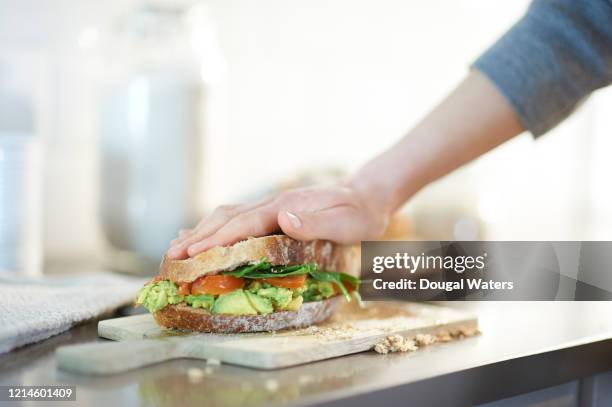 vegan wholemeal bread sandwich with smashed avocado, spinach and tomato filling. - woman sandwich stock pictures, royalty-free photos & images