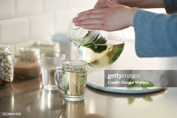 pouring fresh mint tea into glass from glass teapot. - chá de ervas - fotografias e filmes do acervo