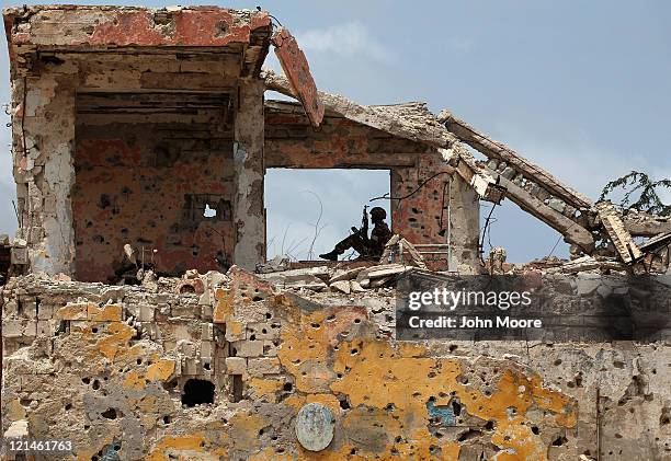 An African Union soldier looks out from war rubble on August 19, 2011 in Mogadishu, Somalia. After two decades of civil war in Mogadishu, the capital...