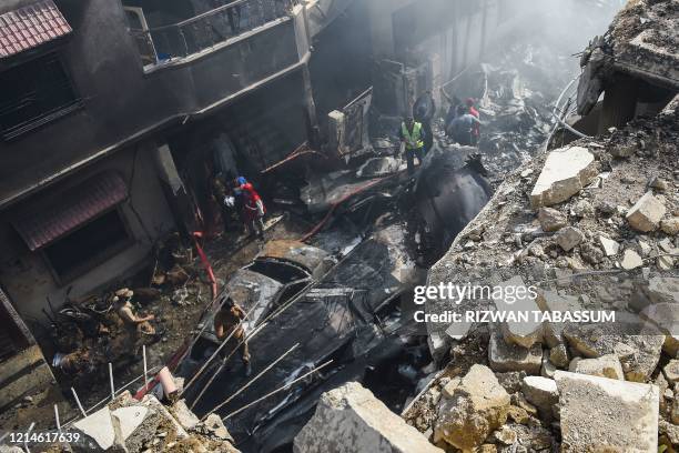 Rescue workers gather at the site after a Pakistan International Airlines aircraft crashed in a residential area in Karachi on May 22, 2020. - A...