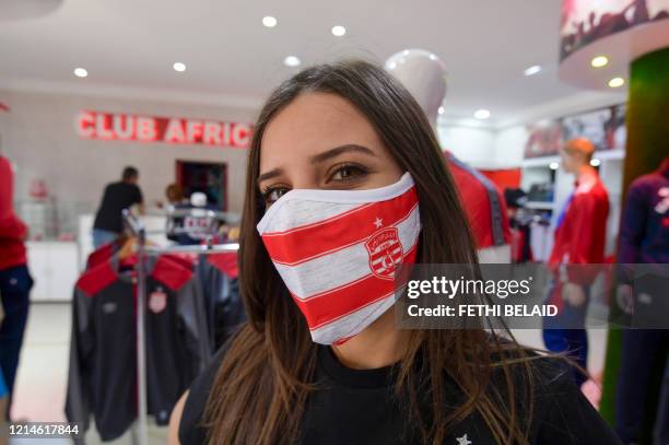 Tunisian girl models a protective face mask bearing the crest and colours of Tunisia's Club Africain at the club store in the capital Tunis on May...