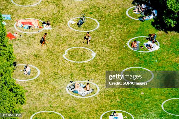 People enjoy the sun at a park during the Ascension Day celebration amid coronavirus crisis. Three meters special circles were developed to help...