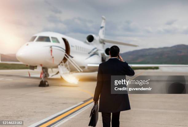 rear view of businessman walking towards private airplane - jets stock pictures, royalty-free photos & images