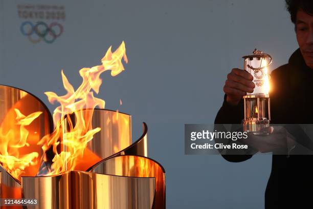 Staff member preserves the Olympic flame to the lantern during the 'Flame of Recovery' special exhibition at Aquamarine Park a day after the...