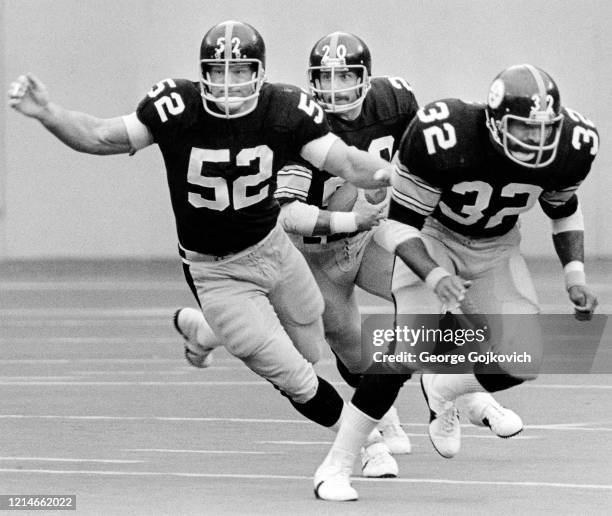 Running back Rocky Bleier of the Pittsburgh Steelers runs with the football behind the blocking of center Mike Webster and running back Franco Harris...