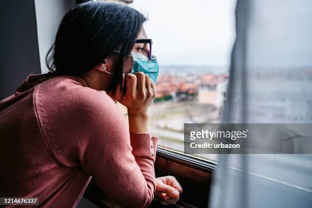 donna in quarantena che guarda attraverso la finestra - isolamento foto e immagini stock