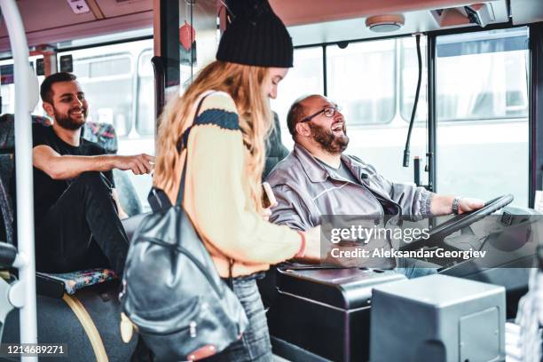 bus driver joking with young female paying for ticket with credit card - driver passenger stock pictures, royalty-free photos & images