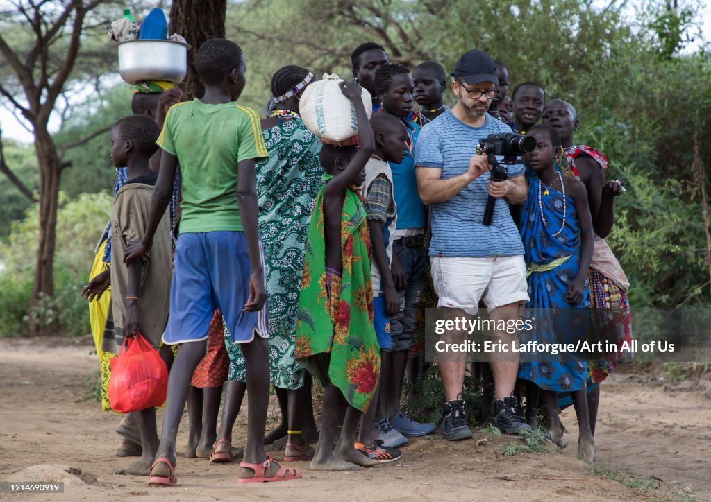 Western tourist filming surrended by Toposa tribe people, Namorunyang State, Kapoeta, South Sudan