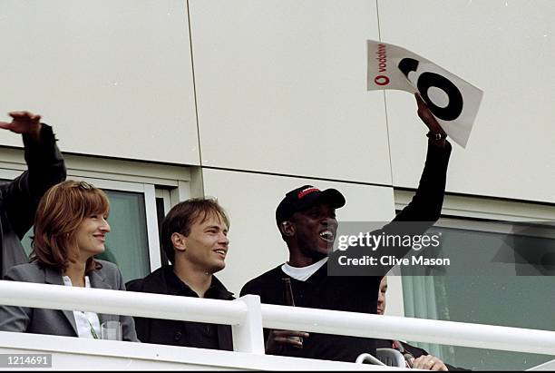 Treble winner Dwight Yorke of Manchester United signals six runs alongside new team mate Mark Bosnich whilst watching the West Indies during the...