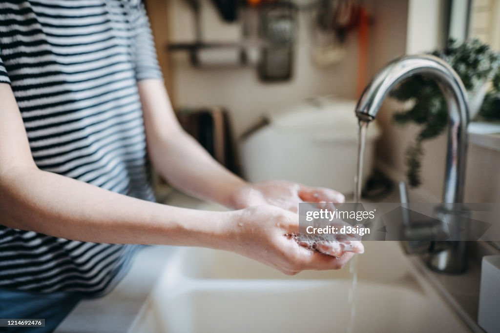 Cropped shot of a woman maintaining hands hygiene and washing hands with soap in the sink