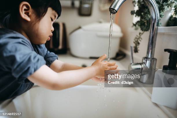 cropped shot of a little asian toddler girl maintaining hands hygiene and washing hands with soap in the sink - child washing hands stock pictures, royalty-free photos & images