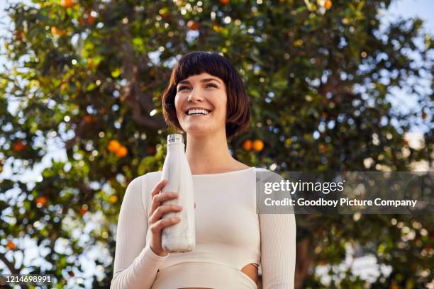 laughing woman drinking water bottle after an outdoor exercise session - drinking from bottle stock pictures, royalty-free photos & images