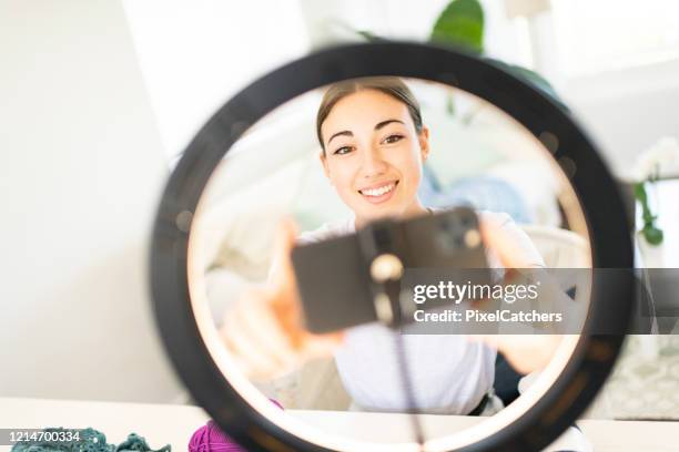 young woman influencer setting up smart phone in ring light - teen doing filming imagens e fotografias de stock