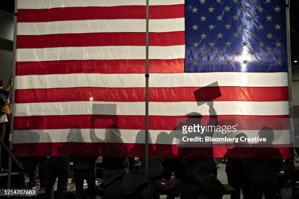 people silhouetted against an american flag - political rally ストックフォトと画像
