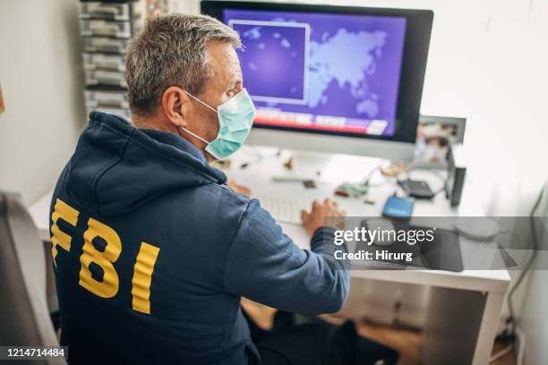 hogere fbi agent met beschermend masker dat in het bureau werkt - fbi agent stockfoto's en -beelden