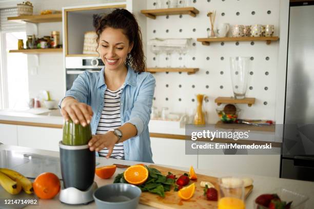 young woman preparing a green smoothie at home - juicing stock pictures, royalty-free photos & images