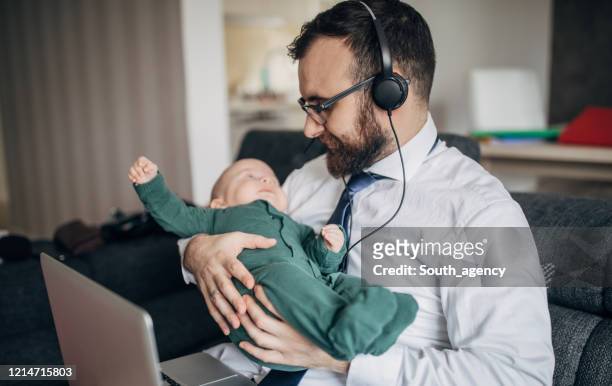 Businessman holding his baby son and working from home do to pandemic outbreak